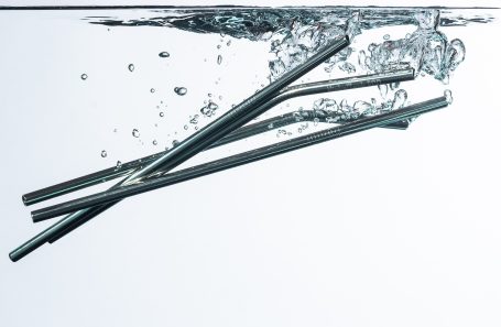 NickelTech Straws Silver straws submerged in clear water with bubbles rising around them.